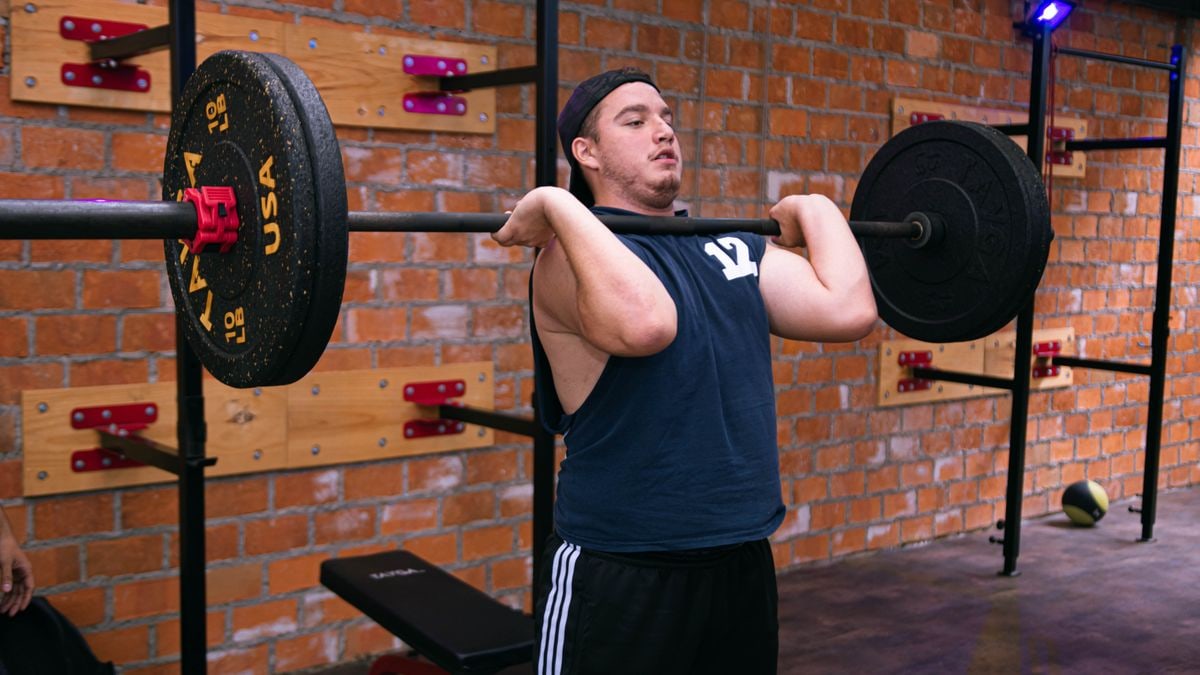 A man focuses on lifting a heavy barbell in a Ciudad de México gym.